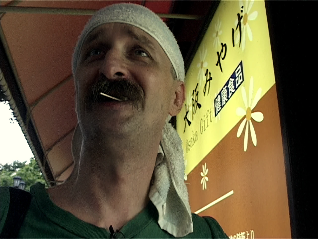 Alfred grinning up at the sky, a towel on his head and a toothpick in his teeth