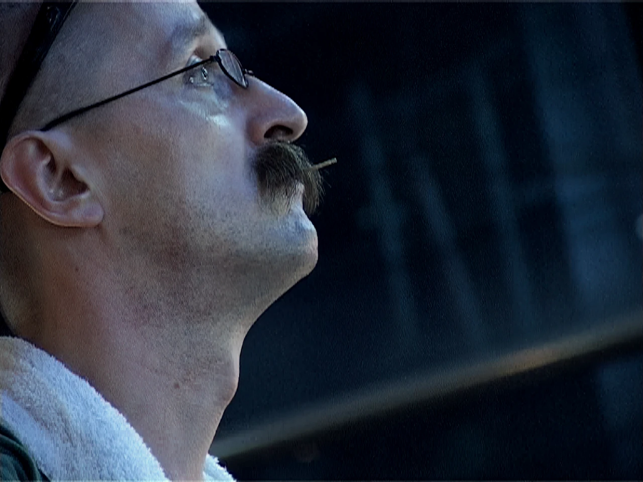 Alfred in profile at night, glasses on, a toothpick under his mustache