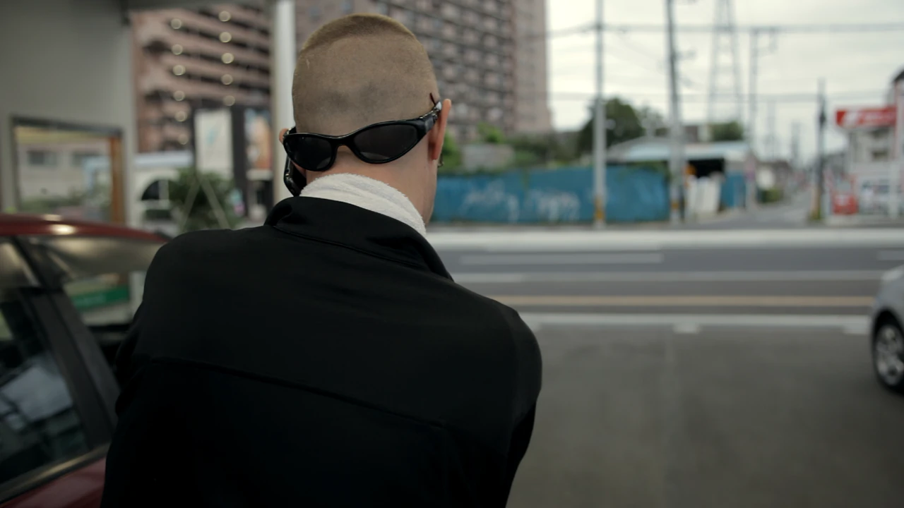 Alfred from behind, his sunglasses pushed onto the back of his shaved head